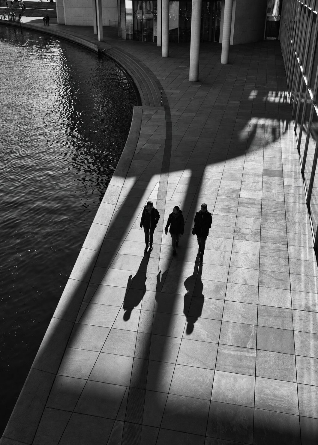 Three professionals crossing a modern institutional plaza